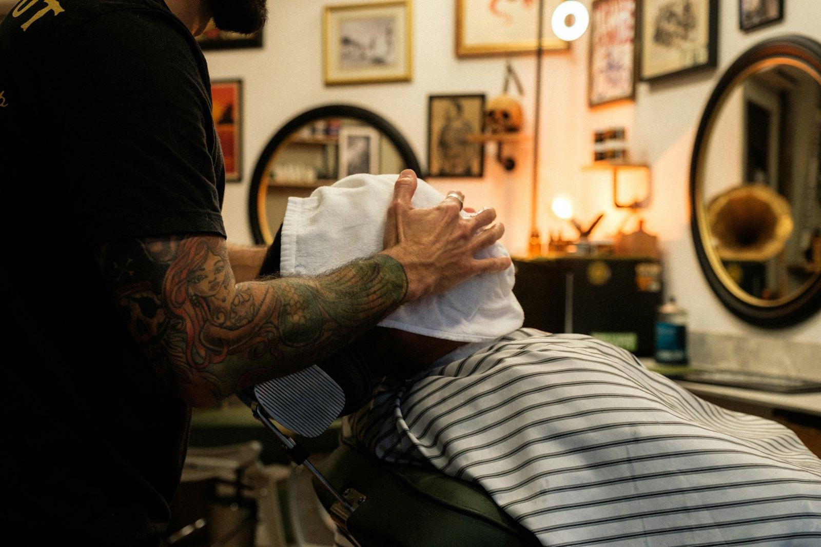 Barbero poniendo una toalla caliente a un cliente
